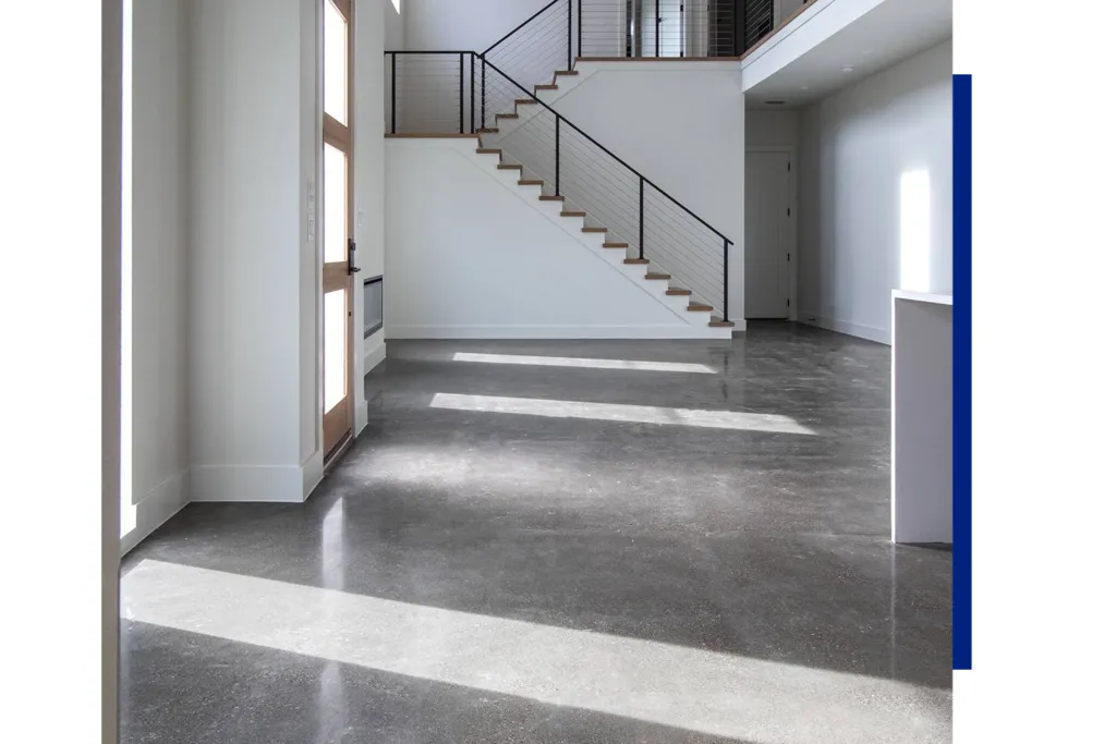 Sunlit modern foyer with staircase and concrete floor