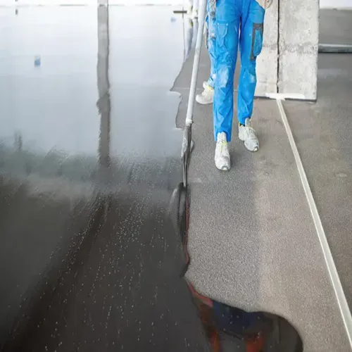 Worker applying black epoxy floor coating